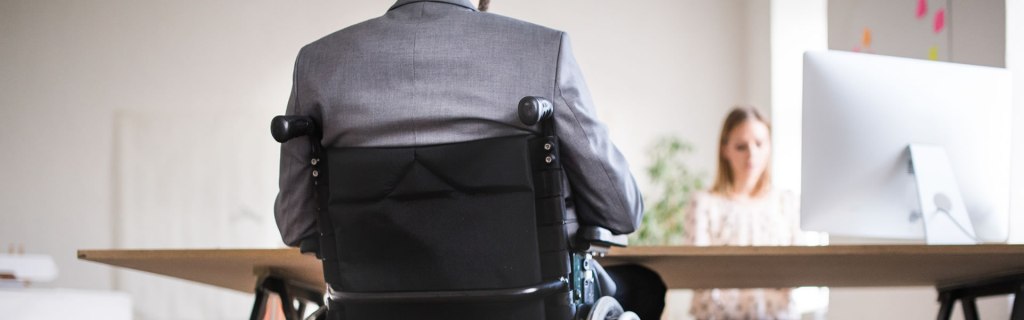 A shot of a businessman in a wheelchair completing a work assignment. A gentleman in a wheelchair completes a work assignment.